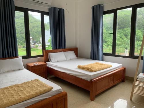 two beds in a room with windows at Cat Ba Rustic Homestay in Cat Ba