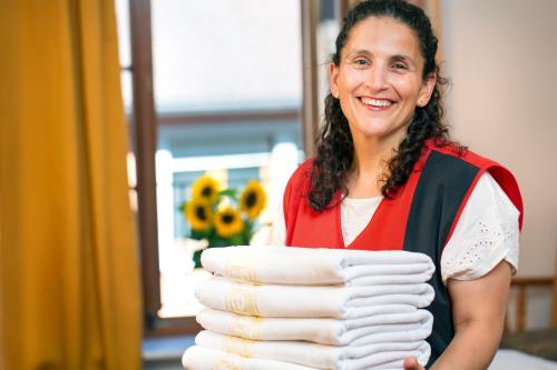 a woman is holding a stack of towels at Hotel der Löwen in Staufen in Staufen im Breisgau