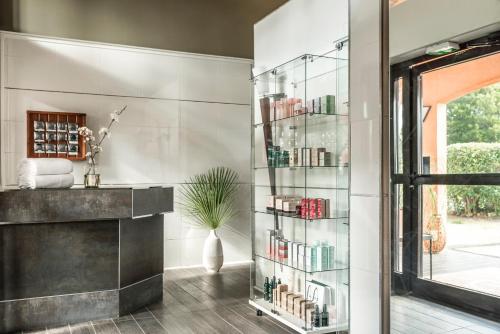 a glass book shelf with books in a room at Golf Hôtel de Valescure & Spa NUXE in Saint-Raphaël