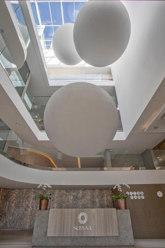 a lobby with a large ceiling with large white lights at Suryaa Hotel Pinhais, Curio Collection by Hilton in Pinhais
