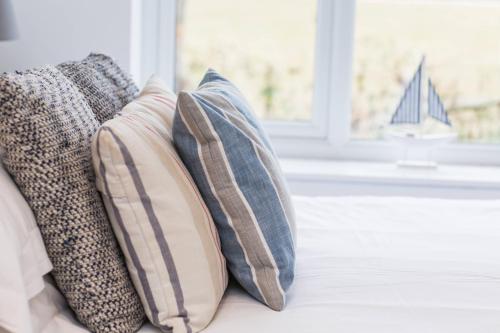 a group of pillows sitting on a couch with a window at Linden House in West Wittering