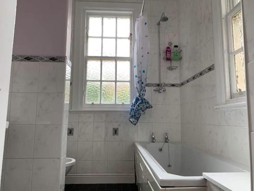 a bathroom with a tub and a toilet and a window at ALTIDO Adorable flat near West End in Edinburgh