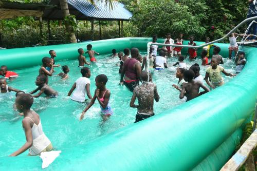 grupa dzieci bawiących się na zjeżdżalni wodnej w obiekcie Adomi Bridge Garden w mieście Adome