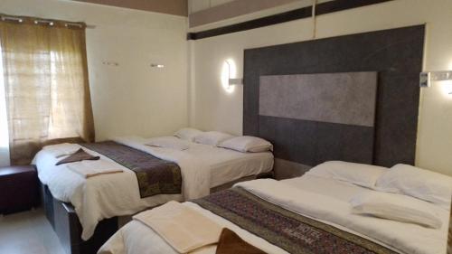 ein Hotelzimmer mit 3 Betten und einem Fenster in der Unterkunft Royal Mughal in Āmbūr