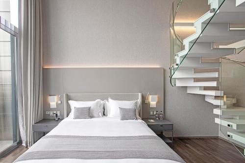 a bedroom with a white bed and a staircase at Suryaa Hotel Pinhais, Curio Collection by Hilton in Pinhais