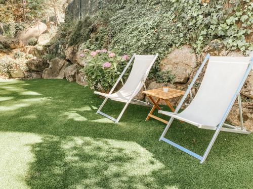 twee ligstoelen en een tafel op het gras bij Villa en el Golf Costa Brava a 5 min de la playa in Santa Cristina d'Aro