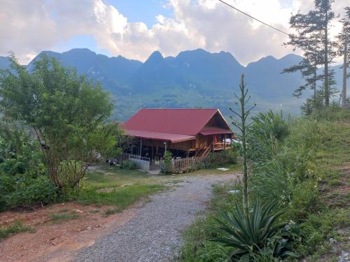 a building with a red roof with mountains in the background at Homestay Hoàng Vũ in Ha Giang
