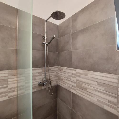 La salle de bains est pourvue d'une douche avec une porte en verre. dans l'établissement Manolakis House, à Kardamaina