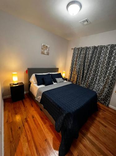 a bedroom with a bed with blue sheets and a window at SPRINGVIEW HOMES 12MINS FROM EWR & 3 MINS FROM UNIVERSITY HOSPITAL in Newark