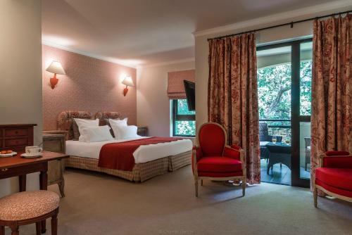 a hotel room with a bed and a red chair at Golf Hôtel de Valescure & Spa NUXE in Saint-Raphaël