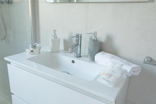 ein weißes Badezimmer mit einem Waschbecken und einem Spiegel in der Unterkunft Cozy Flat Romeo Menti - Vicenza in Vicenza
