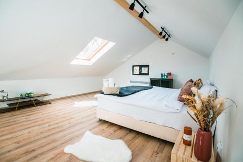a white bedroom with a bed and a wooden floor at Loku' in Vărbilău