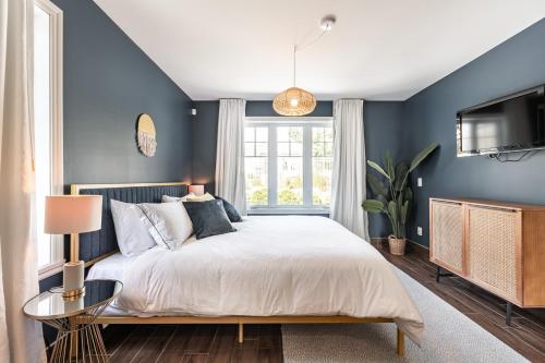 1 dormitorio con paredes azules, 1 cama y TV en Hôtel le Rosay, en Venise-en-Québec
