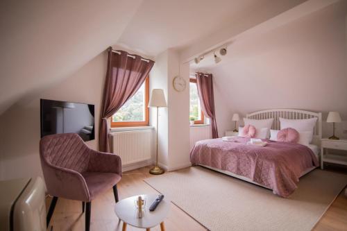 ein Schlafzimmer mit einem Bett mit rosa Kissen und einem Stuhl in der Unterkunft ApartOne Land-Hotel in Sebnitz