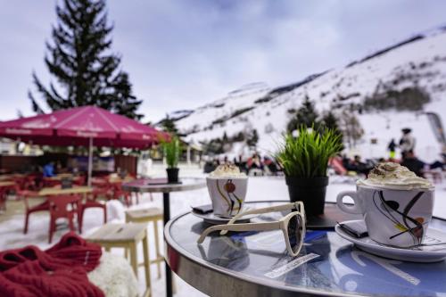 a table with two cups of coffee on top of it at Hôtel Les 2 Alpes L'Orée Des Pistes in Les Deux Alpes