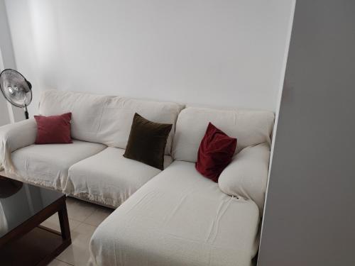 un sofá blanco con almohadas rojas y marrones en Precioso piso en Puerto Real, perfecta ubicación., en Puerto Real