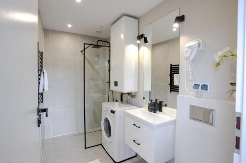 La salle de bains blanche est pourvue d'un lave-linge et d'un lavabo. dans l'établissement Cozy House, à Wisła