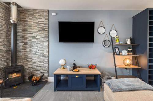 a living room with a tv and a fireplace at Birch Cottage in Tenby