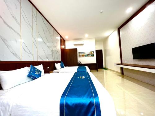 a hotel room with a large bed with a blue blanket at Khách sạn Ngọc Hà in Lao Cai
