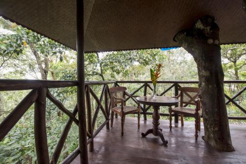 a table and chairs on a porch with a tree at Pepper Trail in Sultan Bathery