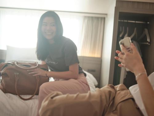 a woman sitting on a bed holding a cell phone at fav HIROSHIMA STADIUM in Hiroshima