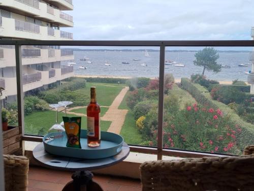 une bouteille de vin posée sur une table devant une fenêtre dans l'établissement Superbe Vue mer T2bis Arcachon, à Arcachon