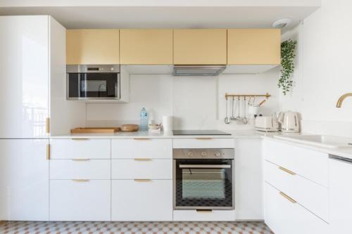 una cocina blanca con armarios y electrodomésticos blancos en La Bella Vita By Plaza, en Chessy