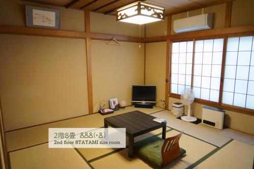 a living room with a table and a tv at Guest House Atagoya in Kyoto