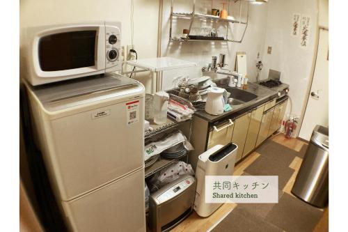 a kitchen with a microwave on top of a refrigerator at Guest House Atagoya in Kyoto