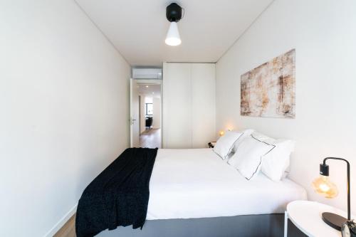 Un dormitorio con una cama blanca y un escritorio. en Lusíadas 53 2ºD - Beautiful two-bedroom apartment, en Lisboa