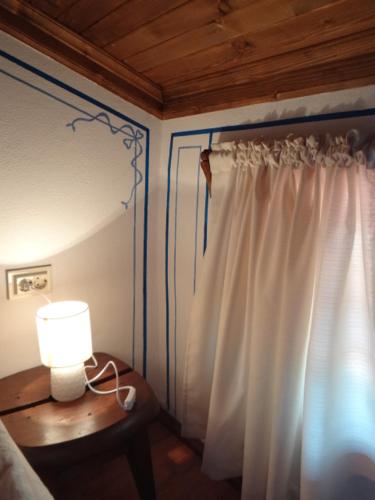 a bedroom with a curtain and a table with a lamp at Недкова къща in Koprivshtitsa