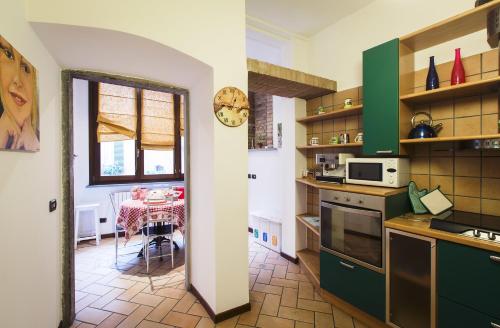 een keuken met groene kasten en een tafel en een klok bij La Rosa Scarlatta in Bergamo