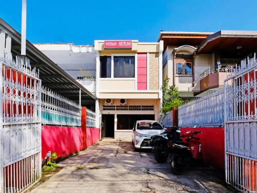 un coche aparcado en un aparcamiento al lado de un edificio en Wisma Seruni Palopo en Palopo