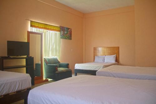 a hotel room with two beds and a chair at OYO Hotel Trigos De Oro,San Luis Teolocholco Park in San Luis Teolocholco