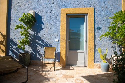 a blue building with a door and a chair at Borgo dei Lecci Puglia in Selva di Fasano