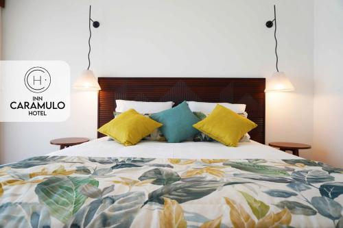 a bedroom with a large bed with yellow and blue pillows at Inn Caramulo Hotel in Tondela