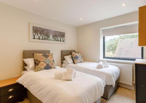 two beds in a room with a window at Fawn Cottage disabled adapted 3 bed cottage in Coughton
