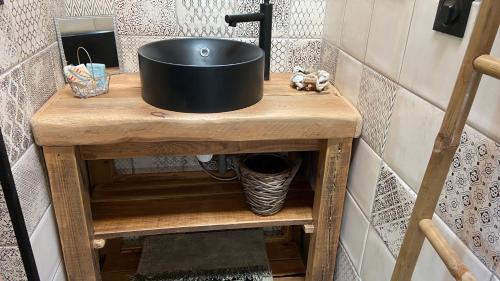 - un lavabo noir sur une table en bois dans la salle de bains dans l'établissement La cabane de marie, à Arès