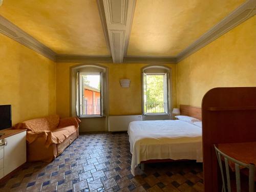 ein Schlafzimmer mit einem Bett, einem Sofa und Fenstern in der Unterkunft Residence Corte della Vittoria in Parma