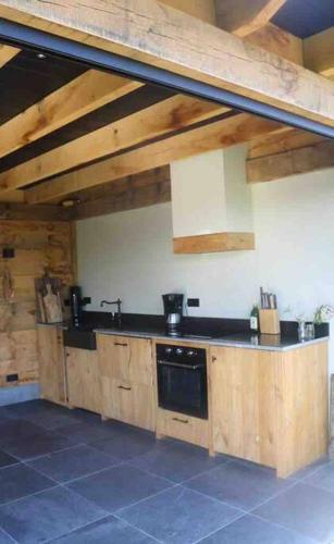 a kitchen with wooden cabinets and a black appliance at Zeeuwse Ontspanning in Kapelle