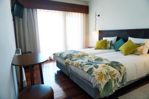 a hotel room with a bed and a table and window at Inn Caramulo Hotel in Tondela