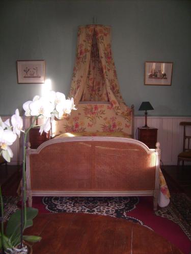 a bedroom with a bed with a canopy and flowers at Chambres d'hôtes & Gîtes du Château de Grand Rullecourt in Grand Rullecourt