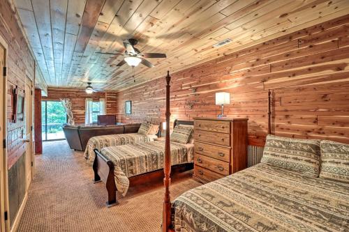a log cabin bedroom with two beds and a tub at Rural Wooded Cabin Near Trophy Trout Fishing! in Norfork