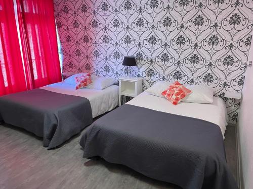 ポワティエにあるホテル オ シャポン ファンのピンクと紫の壁紙を用いた客室内のベッド2台