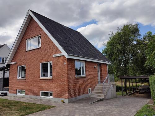 una casa di mattoni rossi con tetto di gamberetti di Bjergby Guesthouse a Hjørring