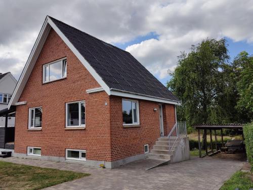 una casa de ladrillo rojo con techo de gambrel en Bjergby Guesthouse, en Hjørring