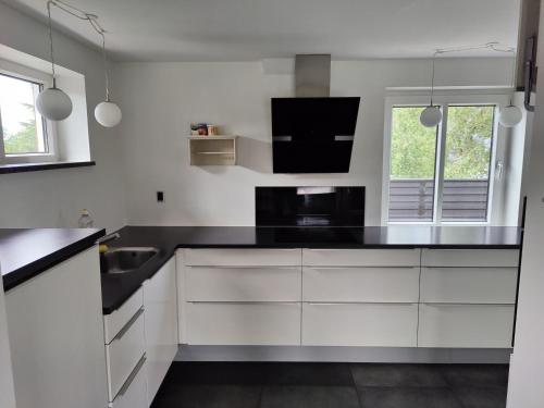 uma cozinha com armários brancos e um balcão preto em Bjergby Guesthouse em Hjørring