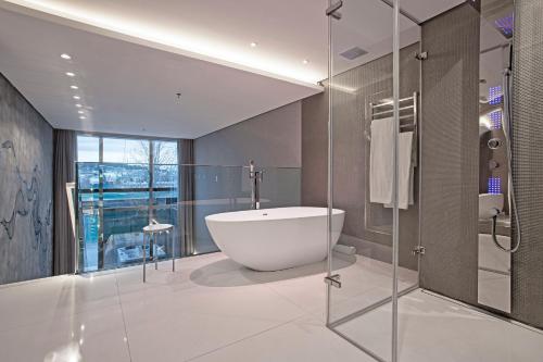 a bathroom with a tub and a glass shower at Suryaa Hotel Pinhais, Curio Collection by Hilton in Pinhais