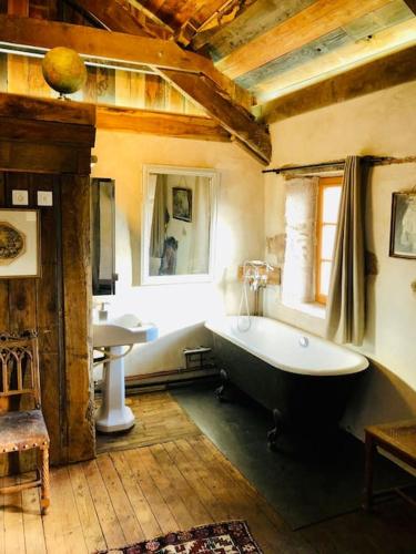 La grande salle de bains est pourvue d'une grande baignoire et d'un lavabo. dans l'établissement La petite Maison du Bonheur & Jacuzzi, à Croze