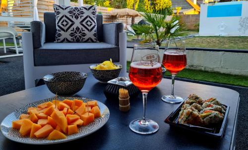 una mesa con dos copas de vino y una bandeja de comida en The White Home Broadway Love Room, en Châteauroux